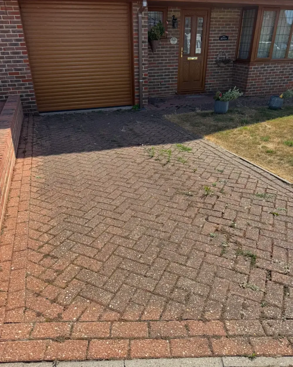 Moss-covered block paved driveway beside a garage before pressure washing