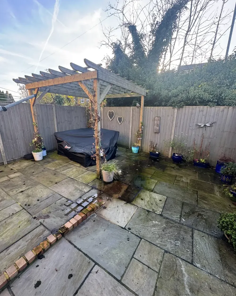 Indian sandstone patio under a pergola, green with algae before cleaning