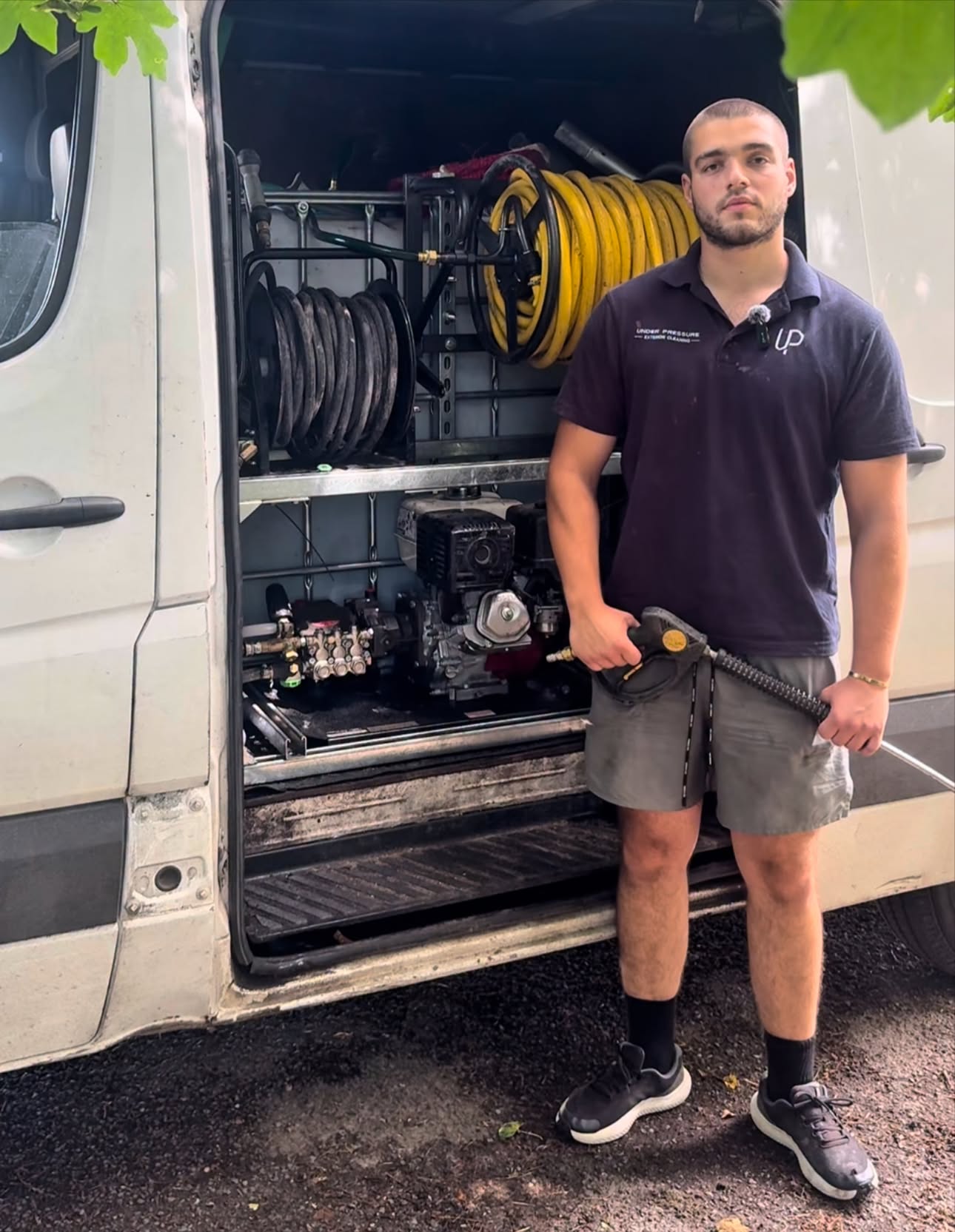 Rez, founder of UP Exterior Cleaning, in branded polo in front of the company van and equipment