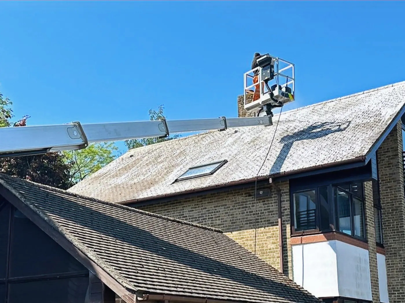 Close view of a tiled roof being cleaned from an access platform