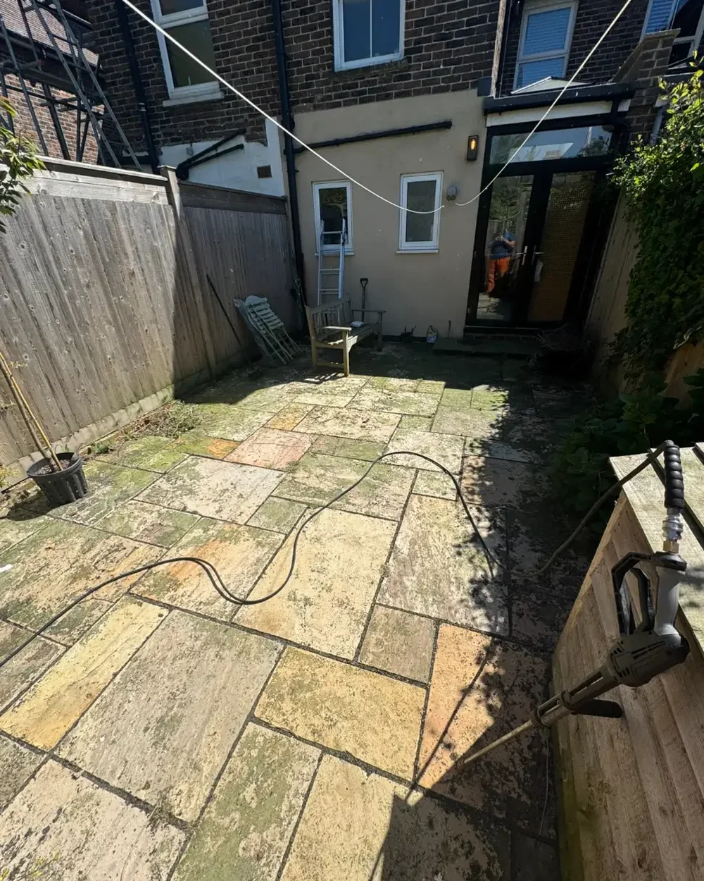Sandstone courtyard patio stained green with algae before pressure washing